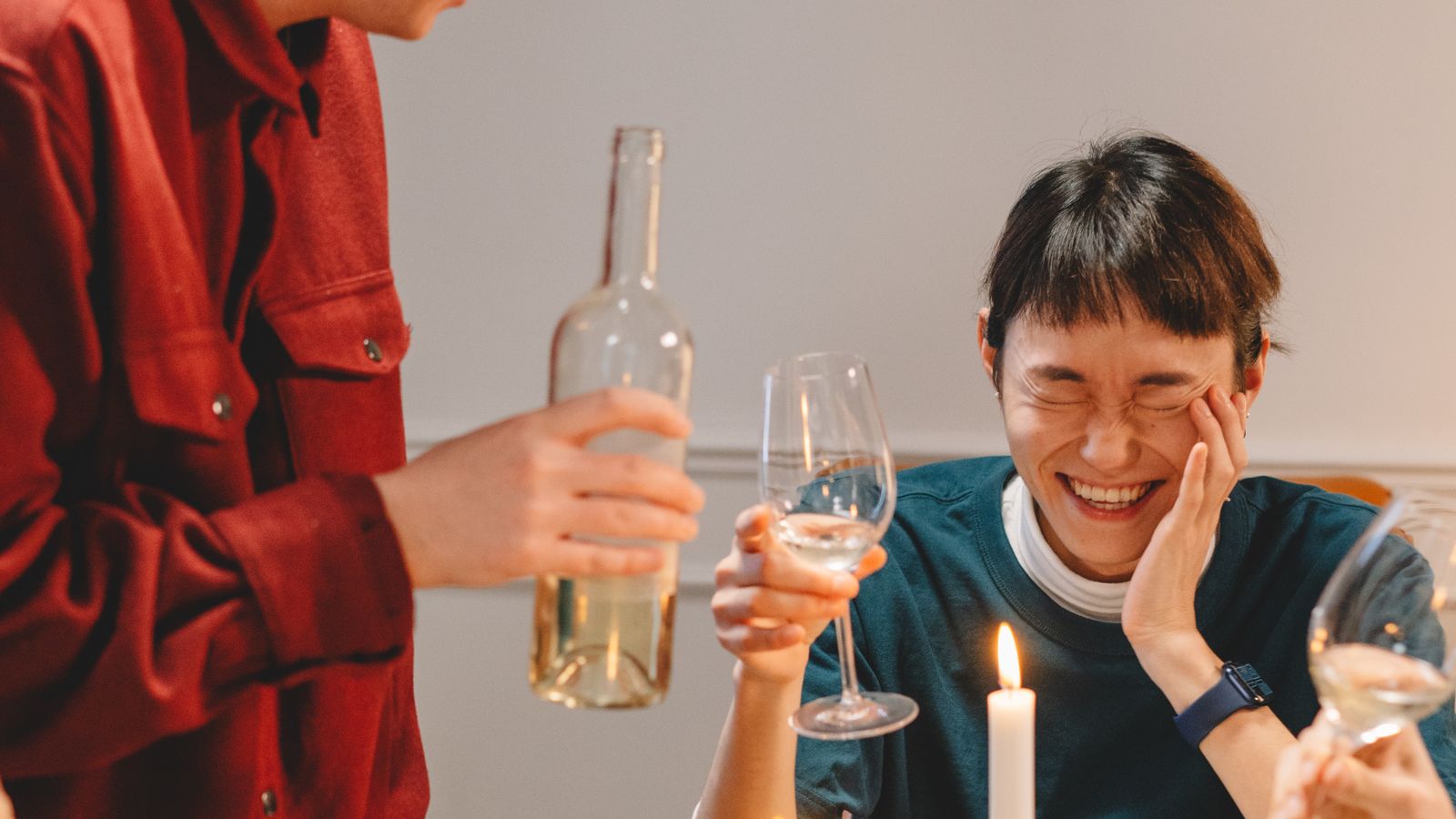 Friends laughing together at a candlelit dinner table