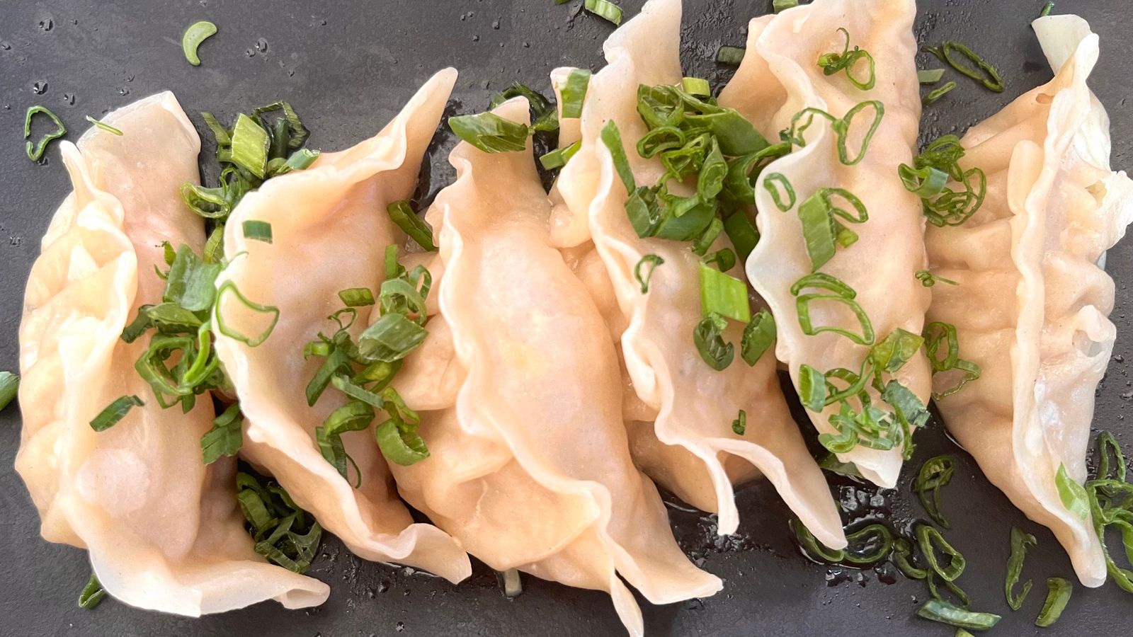 Plate of dumplings topped with scallions